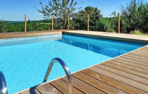 une piscine bleue avec une terrasse en bois dans l'établissement La Grange Aux Noix, à Veyrines-de-Domme