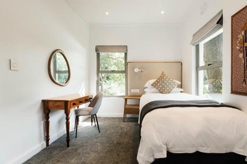 a bedroom with a bed and a desk and a mirror at Vineyard Hotel in Cape Town