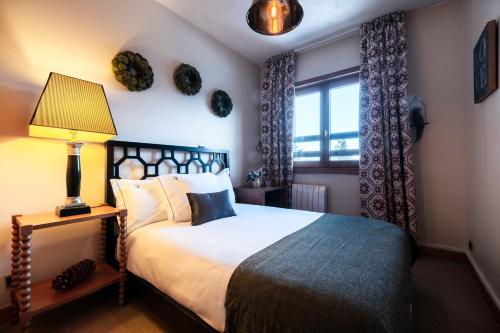 a bedroom with a bed with a lamp and a window at Alpes Hôtel du Pralong in Courchevel
