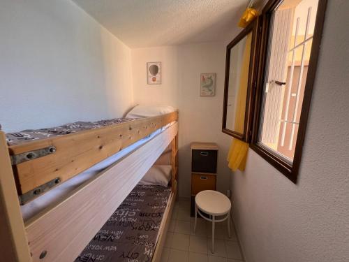 une chambre avec un lit superposé et une chaise dans l'établissement BAIE DES ANGES I Joli T2 cabine piscine proche plage Richelieu Cap d'Agde, au Cap d'Agde