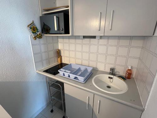 un comptoir de cuisine avec un évier et un micro-ondes dans l'établissement BAIE DES ANGES I Joli T2 cabine piscine proche plage Richelieu Cap d'Agde, au Cap d'Agde