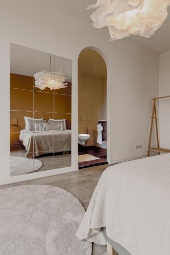 a white bedroom with a bed and a mirror at Ruim 2 Slaapkamer Appartement Met Xl Dakterras in Tilburg