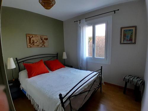 a bedroom with a bed with red pillows and a window at Villa avec piscine près des plages in Nissan-lez-Enserune