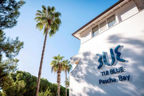 a sign on the side of a building with palm trees at TUI BLUE Pascha Bay in Konaklı