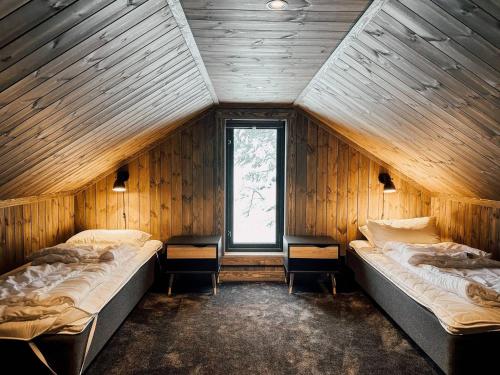 two beds in a wooden room with a window at Modern Mountain Cabin - Sauna - 5 Bedrooms - Sleeps for 10 in Torpo