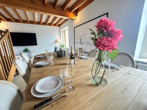 a dining room table with a vase of pink flowers at S Baylevéd'Air duplex vue château, Balnéo et sauna in Sedan