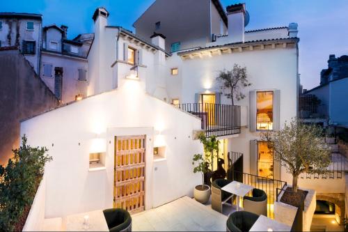 a white house with tables and chairs in front of it at Spirito Santo Palazzo Storico - Adults Only in Rovinj