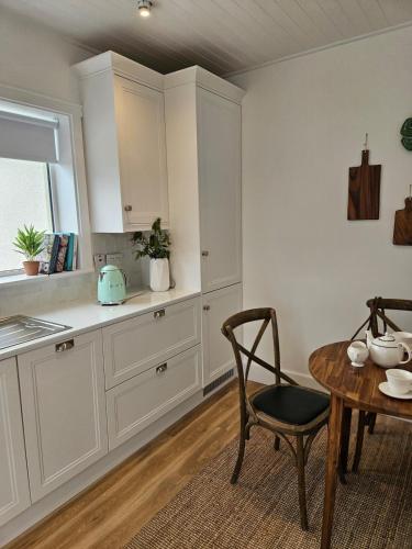 a kitchen with white cabinets and a table and a chair at Three bedroom cosy quiet luxury in the Burren Wild Atlantic Way in Galway