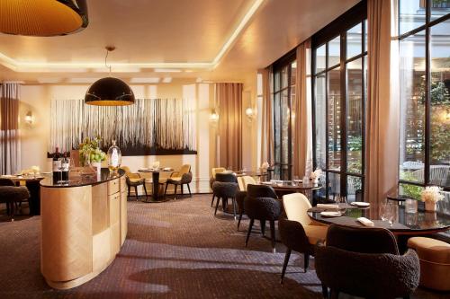 a restaurant with tables and chairs and windows at Le Burgundy Paris in Paris