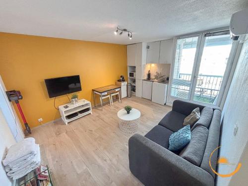 un salon avec un canapé et une télévision à écran plat dans l'établissement Sable d'or Carnon Plage, à Mauguio