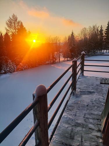 a fence in the snow with the sunset in the background at Przystanek Gorce in Nowy Targ