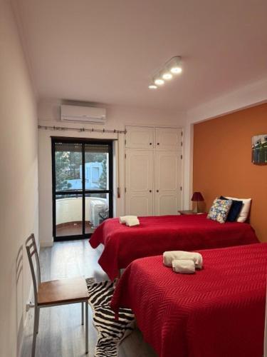 a bedroom with two beds with red sheets and a window at Beach, surf and golf apartment near Lisbon in Aroeira