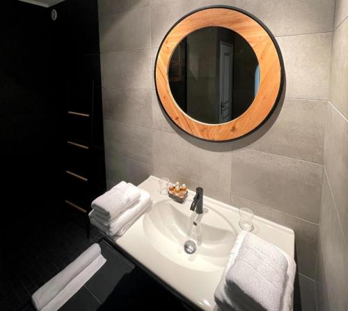 a bathroom with a sink with a round mirror at Le Mas de Camassade in Tourrettes-sur-Loup