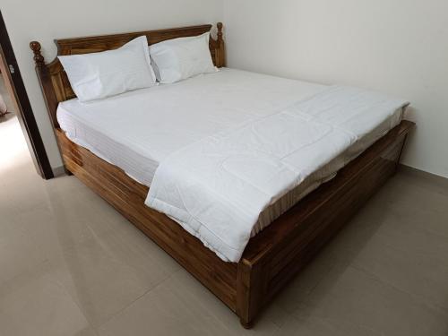 プネにある1BHK Service Apartment 19の木製ベッド(白いシーツ、枕付)