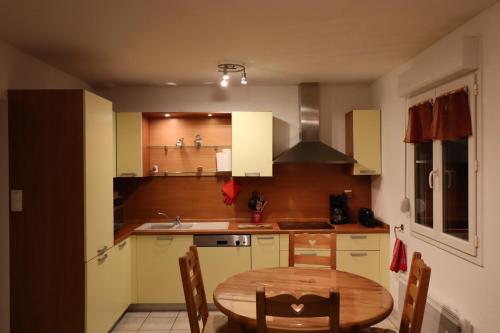 Il comprend une cuisine avec une table en bois et un évier. dans l'établissement Apartment Location Les balcons de La Mauselaine, à Gérardmer