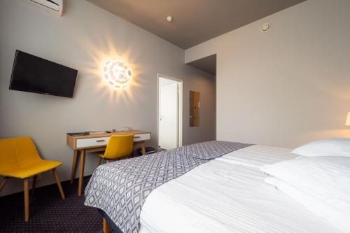 a bedroom with a bed and a desk and a television at Centrum Hotel Viljandi in Viljandi