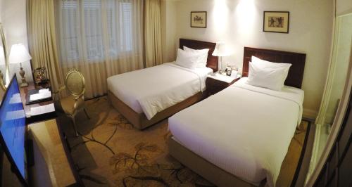 a hotel room with two beds and a desk at Apricot Hotel in Hanoi