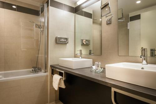 a bathroom with two sinks and a mirror and a shower at Domaine du Gouverneur, Hôtel, Restaurant & Golf in Monthieux