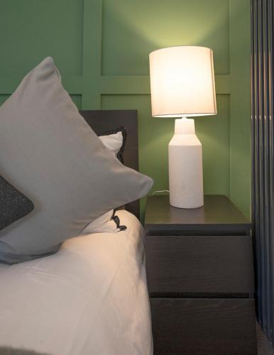 a bed with a pillow and a lamp on a nightstand at Barmouth High Street Family Apartment in Barmouth