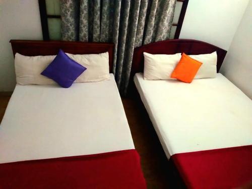 two beds with colorful pillows sitting next to each other at Salmanel Resort Ayagama - Rathnapura in Ratnapura