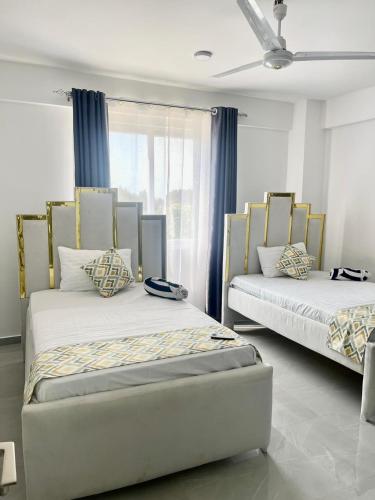 zwei Betten in einem Zimmer mit blauen Vorhängen in der Unterkunft Aqua Luxury homes in Mombasa