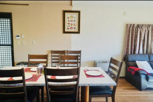 a dining room with a table and chairs and a couch at Foresta Karuizawa 3 in Miyota