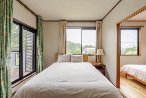 a bedroom with a bed and two windows at Foresta Karuizawa 3 in Miyota