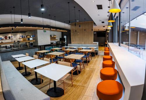 a restaurant with white tables and orange seats at ibis budget Logroño Centro in Logroño