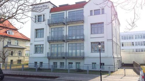ein weißes Gebäude mit Balkonen an der Straßenseite in der Unterkunft Ferienwohnung Warnemünde - L (N) in Warnemünde