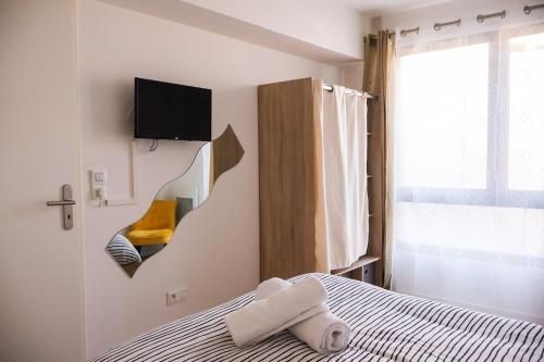 - une chambre avec un lit et une télévision murale dans l'établissement Sahara - appartement ensoleillé au cœur de Reims, à Reims