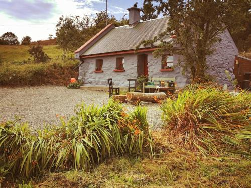 a white cottage with a table and a bench in front of it at Mountain Cottage with Barn Sauna, Clonbur, Galway in Clonbur