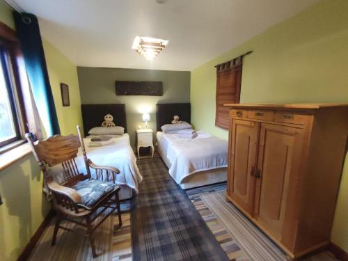 a bedroom with two beds and a chair and a window at Mountain Cottage with Barn Sauna, Clonbur, Galway in Clonbur