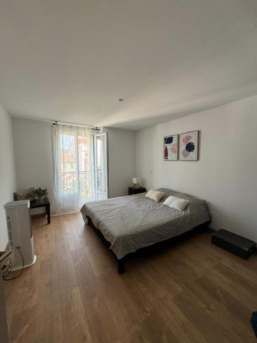 une chambre avec un lit et une grande fenêtre dans l'établissement Charmant T3 centre ville proche gare Perpignan, à Perpignan