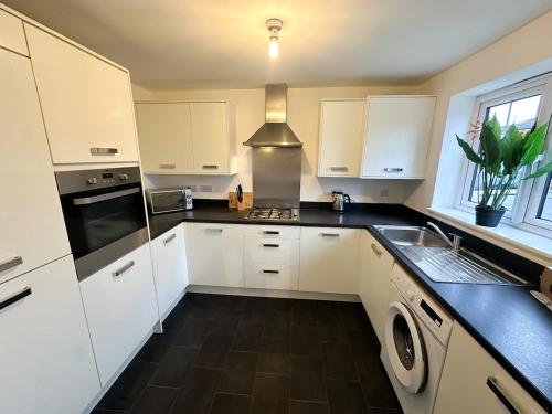 a kitchen with white cabinets and a black counter top at No 9 by Blue Skies Stays in Thornaby on Tees