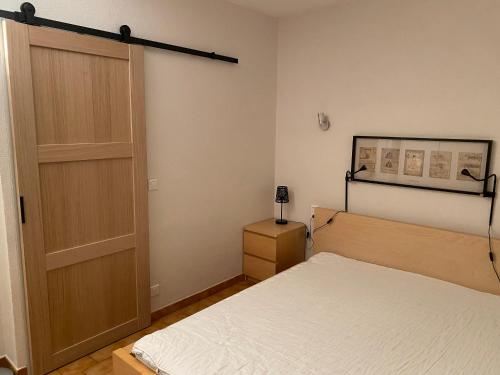 - une chambre avec un lit et une porte en bois dans l'établissement Séjour au pied du colorado provençal, avec piscine, à Rustrel