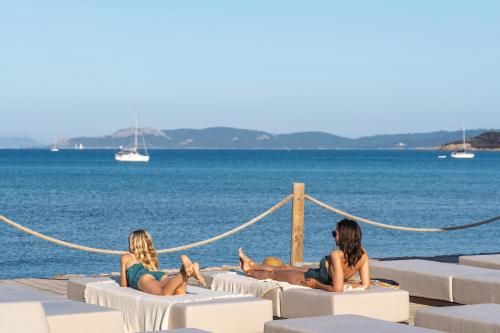 2 femmes assises sur des chaises longues sur la plage dans l'établissement Belambra Clubs Presqu'île De Giens - Riviera Beach Club, à Hyères