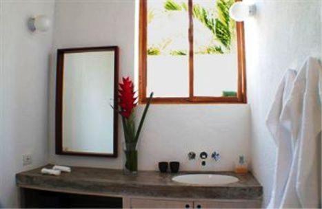 a bathroom with a sink and a vase with a red flower at Los Patios Hotel Granada in Granada