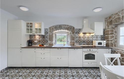 a kitchen with white cabinets and a brick wall at Villa Laura Ripenda in Ripenda Kras