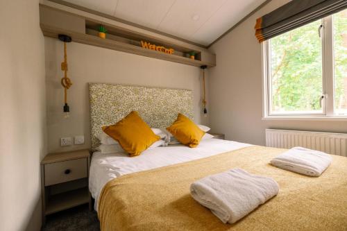 a bedroom with two beds with yellow pillows and a window at Castlewood Holiday Park in Antrim