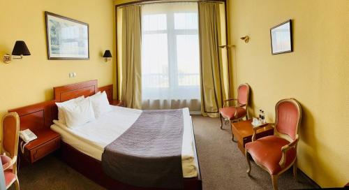 a hotel room with a bed and chairs and a window at Готель Дніпро in Kyiv