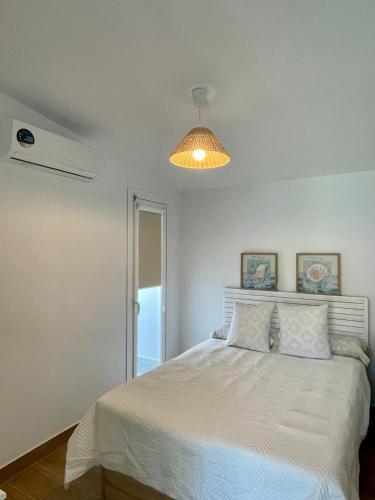 ein Schlafzimmer mit einem weißen Bett und einer Lampe in der Unterkunft Casa Rural El Almendro in Olvera