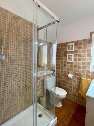 ein Badezimmer mit Toilette und Glasdusche in der Unterkunft Casa Rural El Almendro in Olvera