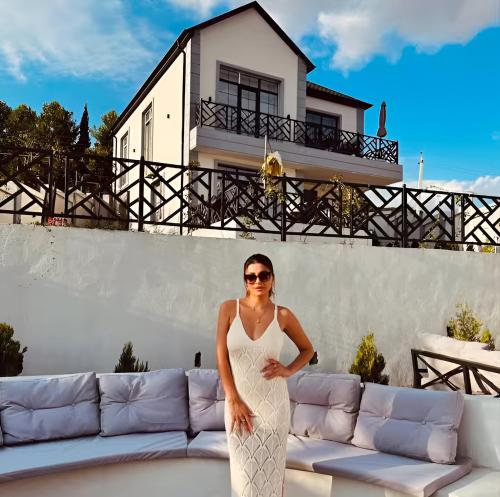 a woman in a white dress standing in front of a couch at White Harmony Houses in Şamaxı