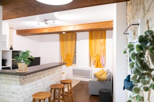- une cuisine et un salon avec des rideaux et des tabourets jaunes dans l'établissement Plein cœur Historique de Caen - Quartier animé - au pied des boutiques, bars et restaurants, à Caen