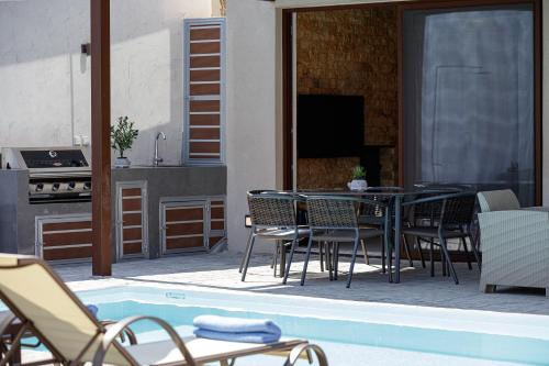 a patio with a table and chairs next to a pool at Villa Fotinou Heated Pool & Free Bikes awaits in Fotinós