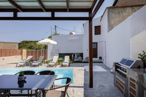 a patio with a table and a kitchen and a pool at Villa Fotinou Heated Pool & Free Bikes awaits in Fotinós