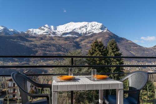 a table and chairs on a balcony with a snow covered mountain at Bellavista - Residence in Barzio center near free ski shuttle in Barzio