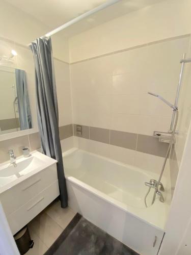 une salle de bain avec une baignoire blanche et un lavabo dans l'établissement Studio avec piscine à 5 min de la plage, à La Seyne-sur-Mer