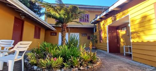 a house with a courtyard with chairs and a palm tree at Pousada Toca das Bromelias in Campos do Jordão