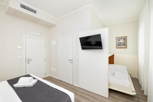 a white bedroom with a bed and a tv at Hotel Maggiore in Bologna